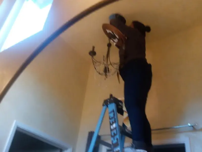 Electrician installing a chandelier in a North Shore residence